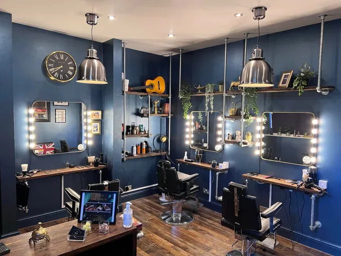Inside Butler’s Barbering — navy walls, bulb-lit mirrors, leather barber chairs and reclaimed wood