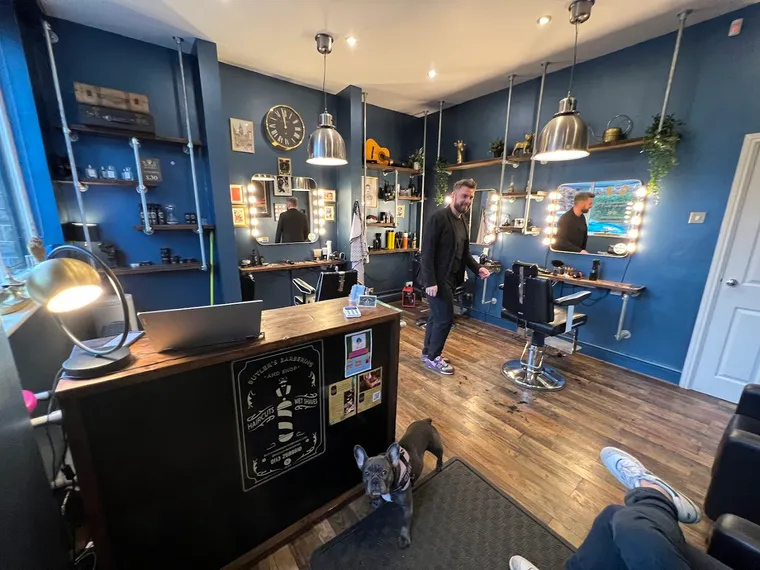 Inside Butler’s Barbering — the owner by the chairs with the shop’s French bulldog